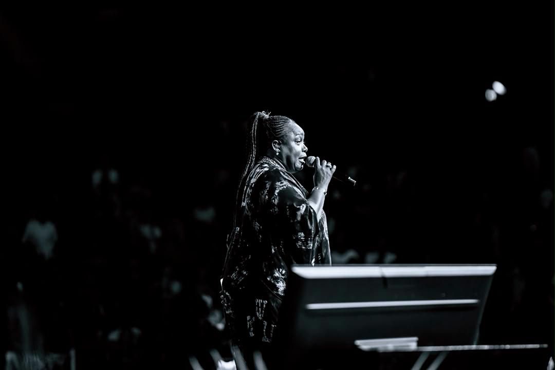 Black-and-white portrait of Chevelle Franklyn singing into a microphone at All Women Together 2026, Kigali.