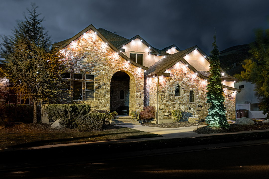 Stone house lit with white lights at night.