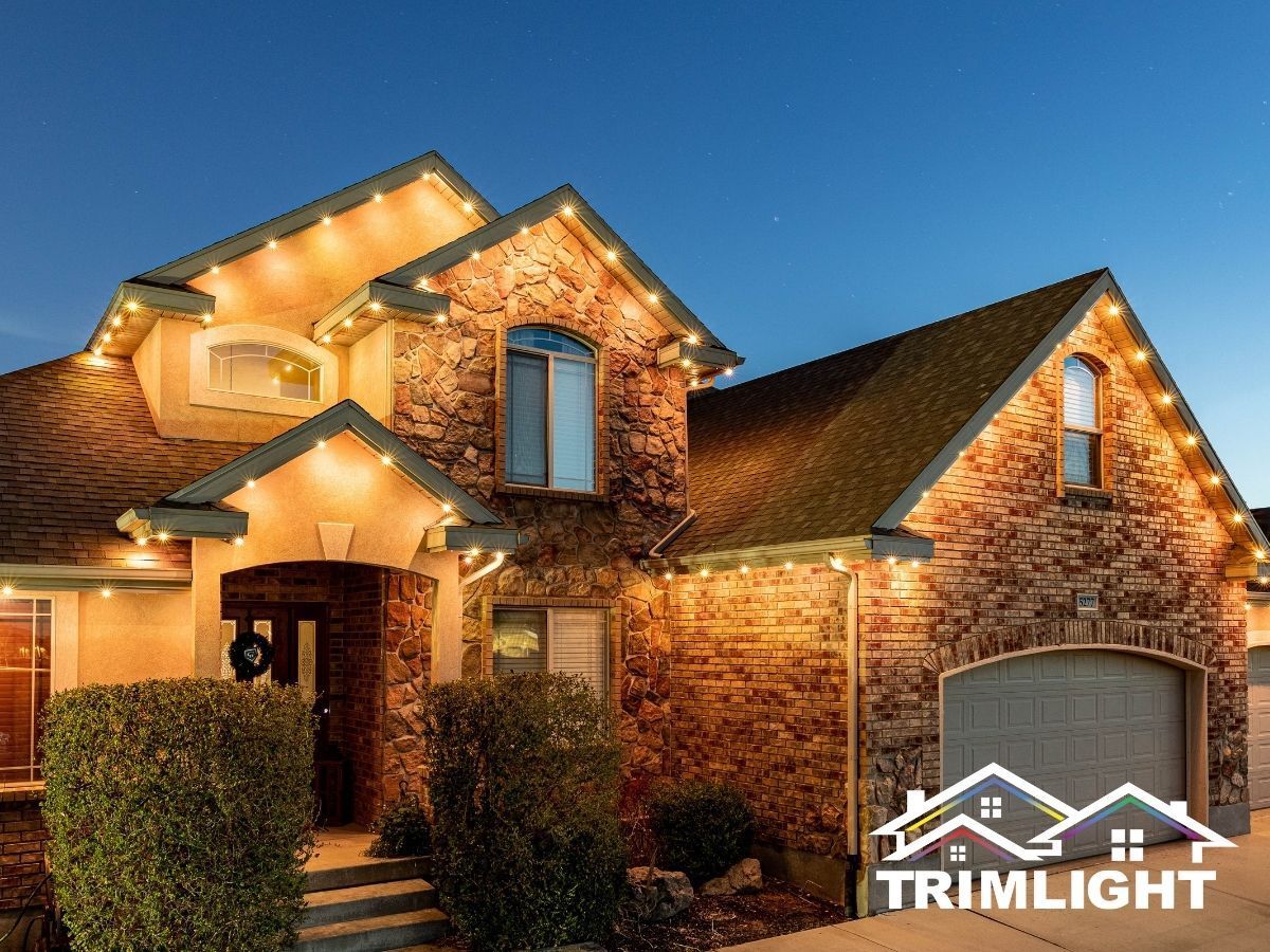 House exterior with roofline and trim lighting glowing warm, with clear sky.