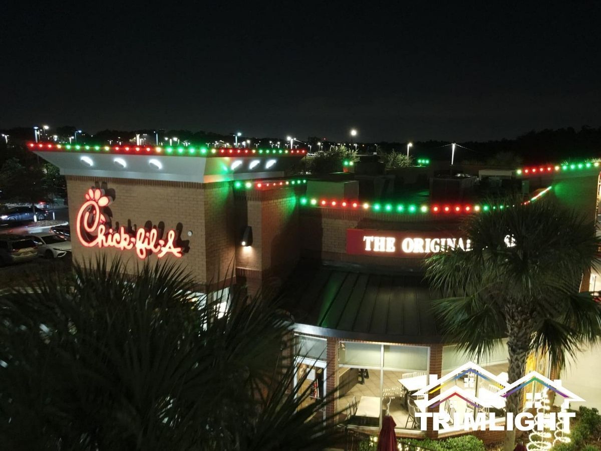 Chick-fil-A restaurant at night with green and red Christmas lights on roofline.