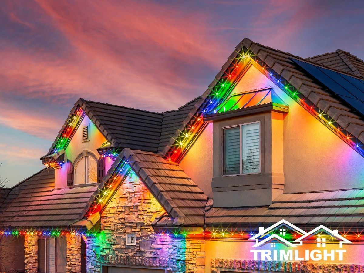 House with colorful LED lights outlining the roof against a sunset sky.