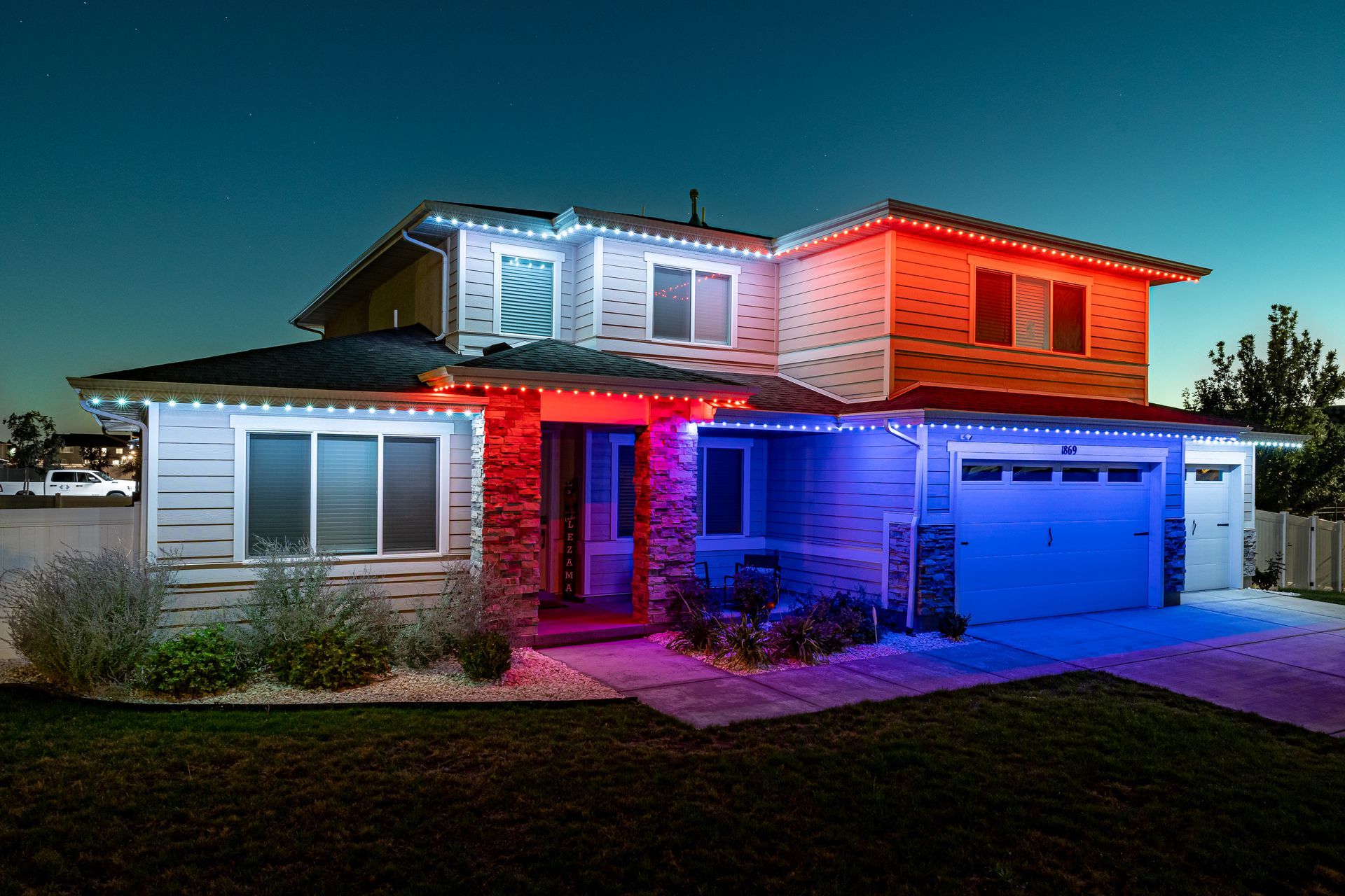 House exterior illuminated with red, white, and blue lights, representing a patriotic theme, at dusk.