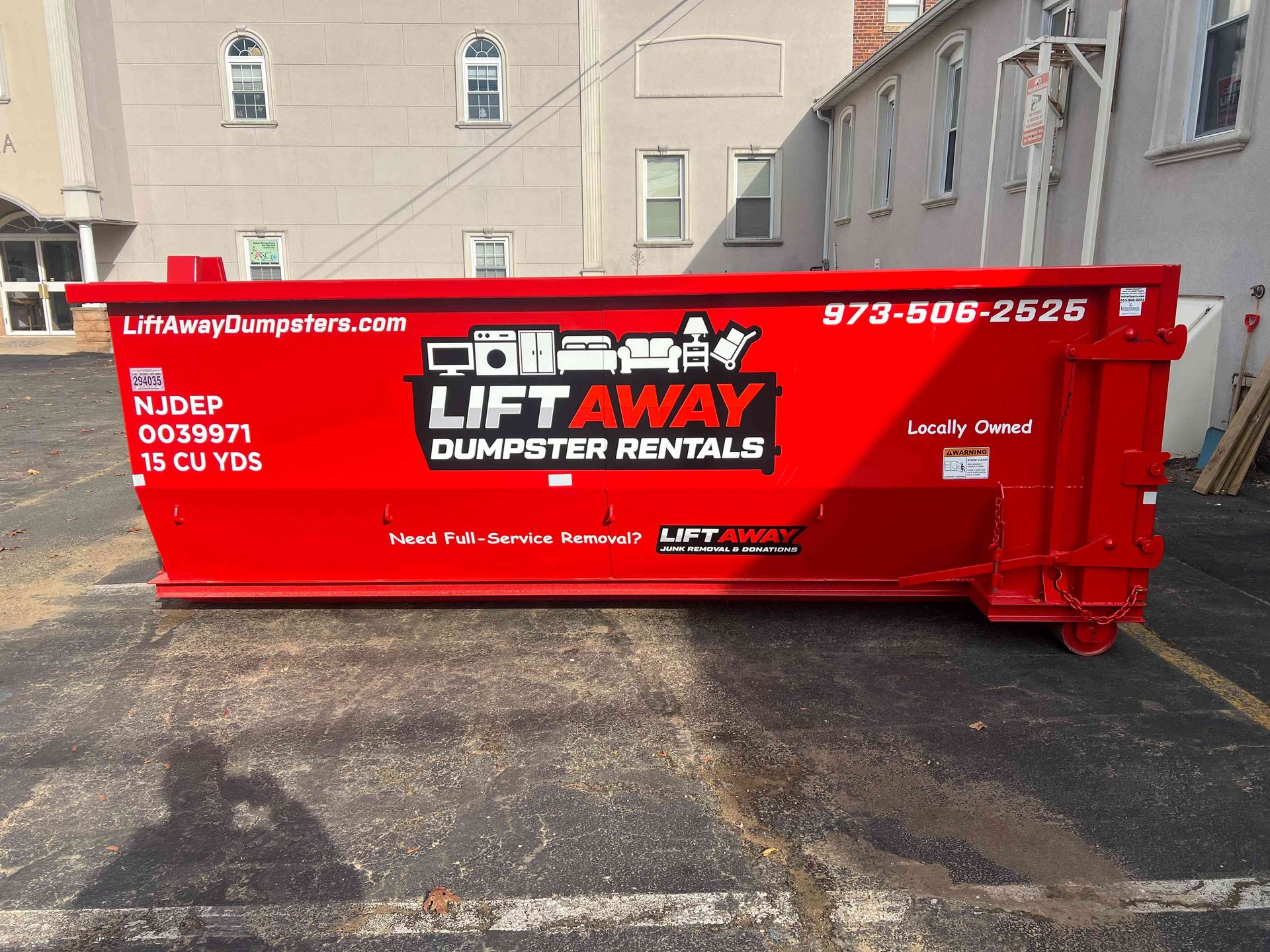 Red Lift Away dumpster in a parking lot.