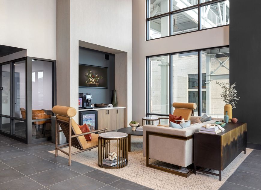 Modern lobby lounge with sofas, chairs, tables, and large windows in a bright interior