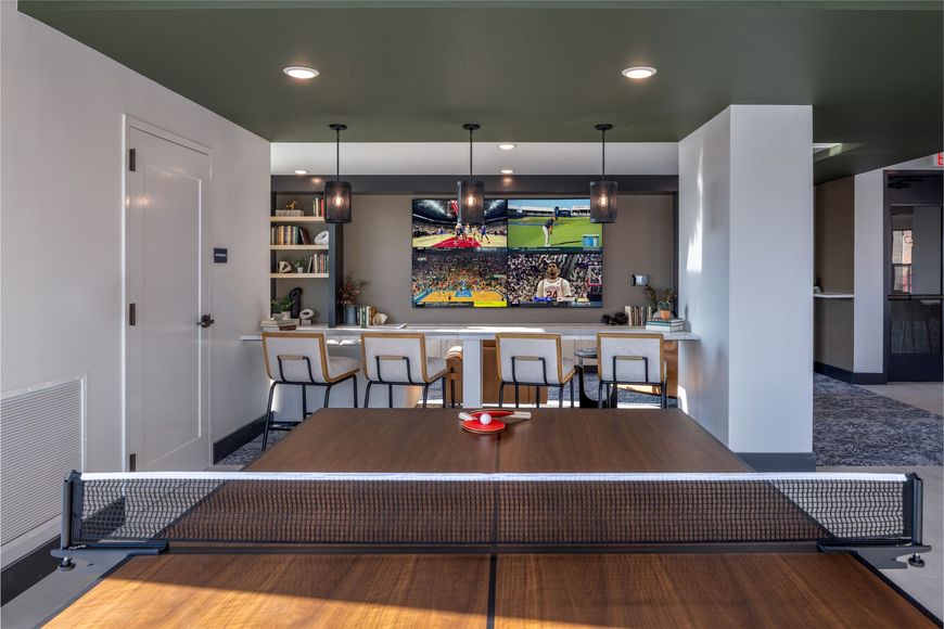 Modern living room with a low sofa, bar seating, and a wall-mounted TV above a fireplace