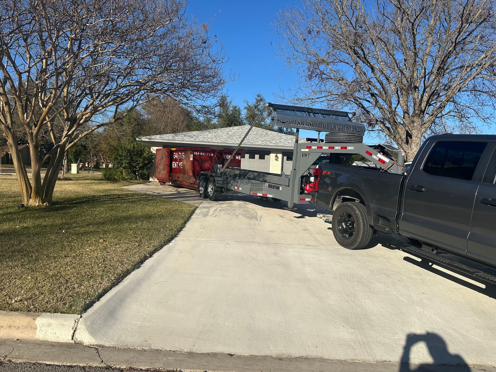 A green dumpster is parked in front of a house.