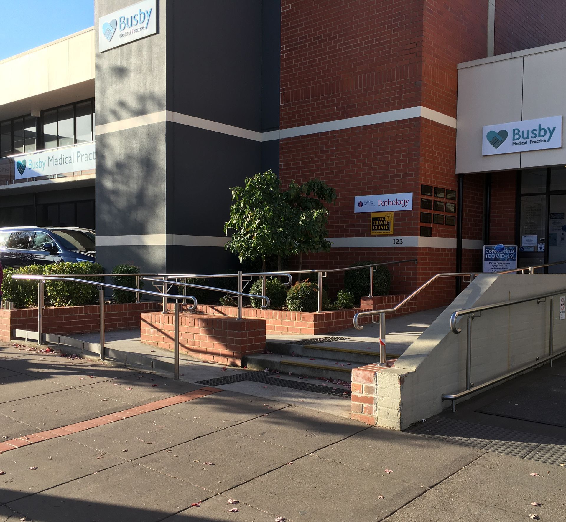 Brick building entrance with ramp, stairs, and a Busy sign in front