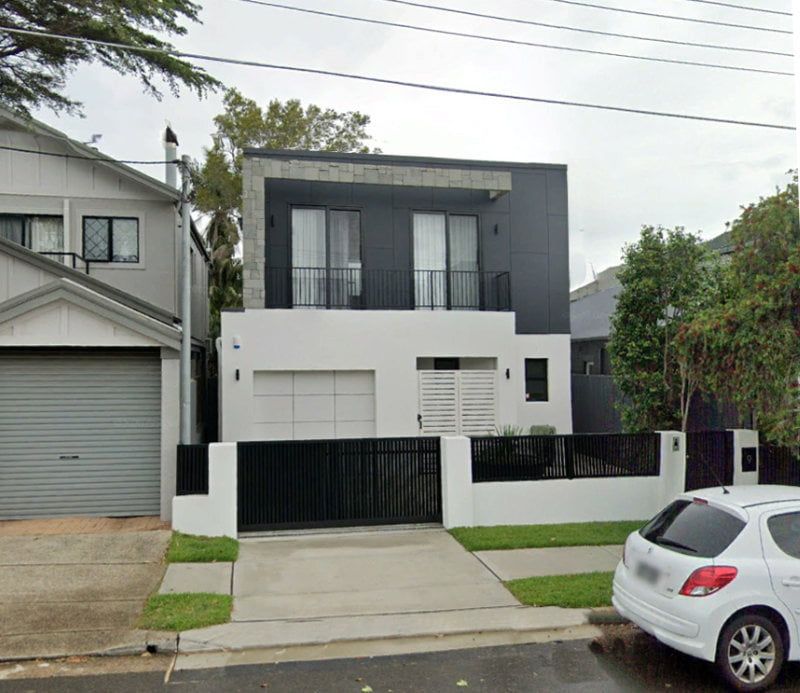 Modern two-story black-and-white house with garage and front gate on a residential street