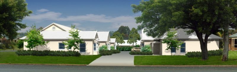 Residential neighborhood with white houses, green lawns, and a tree-lined driveway under a blue sky