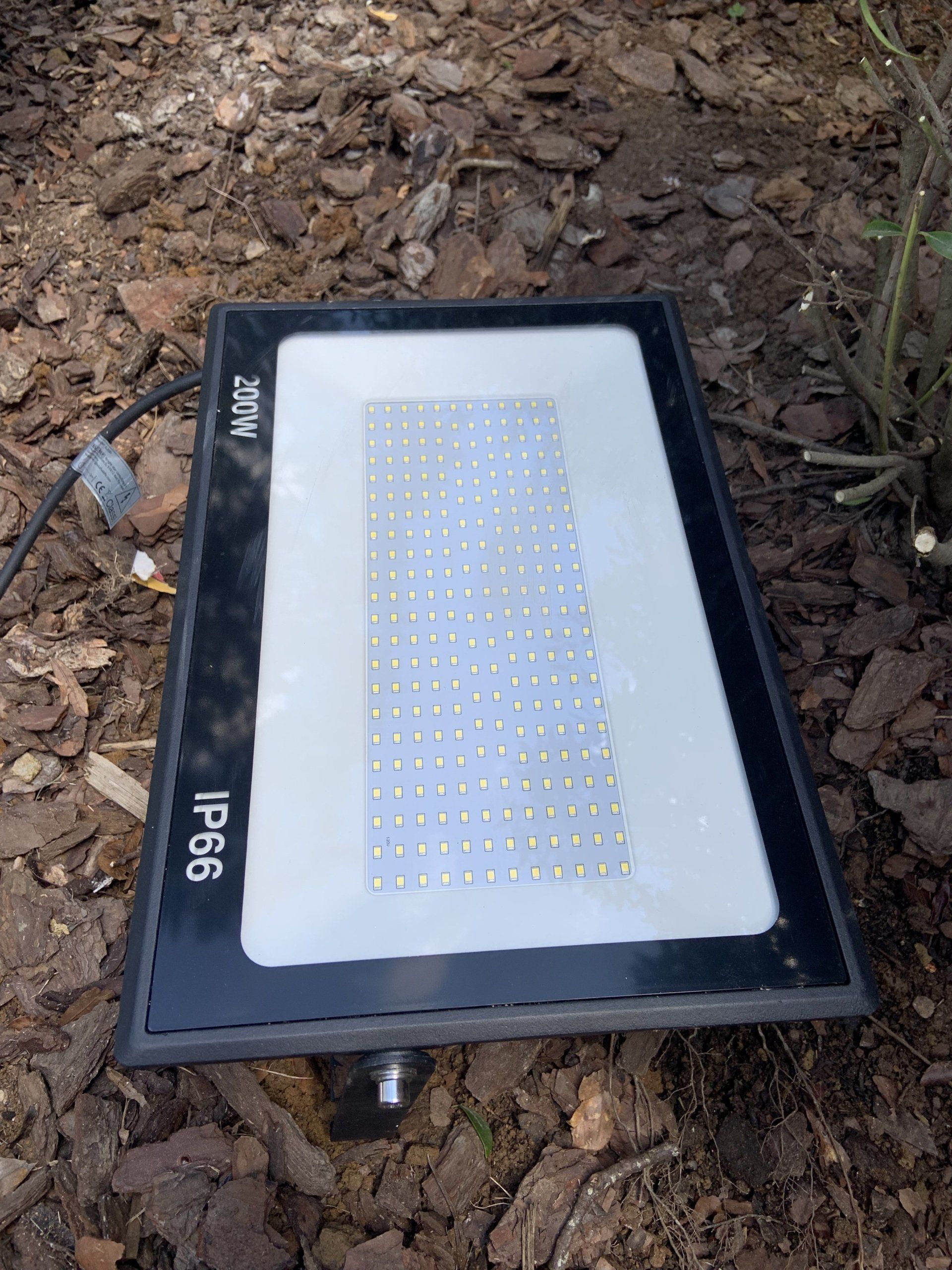 A flood light is sitting on top of a pile of dirt.