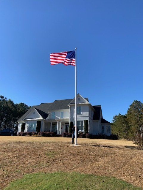A large american flag is flying in front of a house.