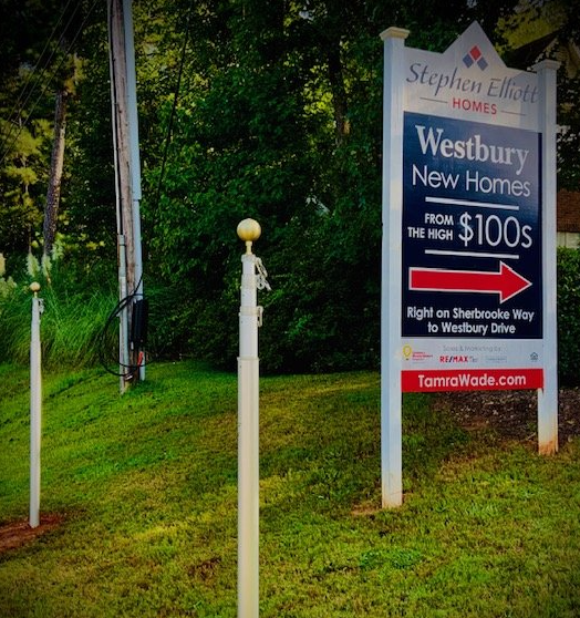 A sign for westbury new homes has an arrow pointing to the right