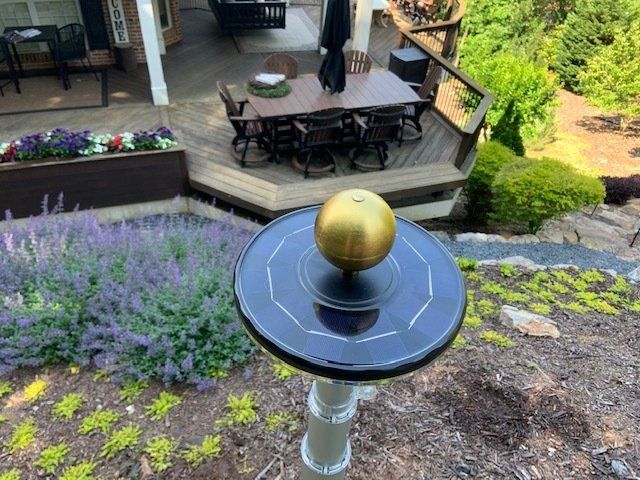 A gold ball is sitting on top of a black table in front of a deck.