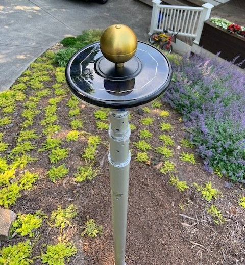 A pole with a ball on top of it in a garden.
