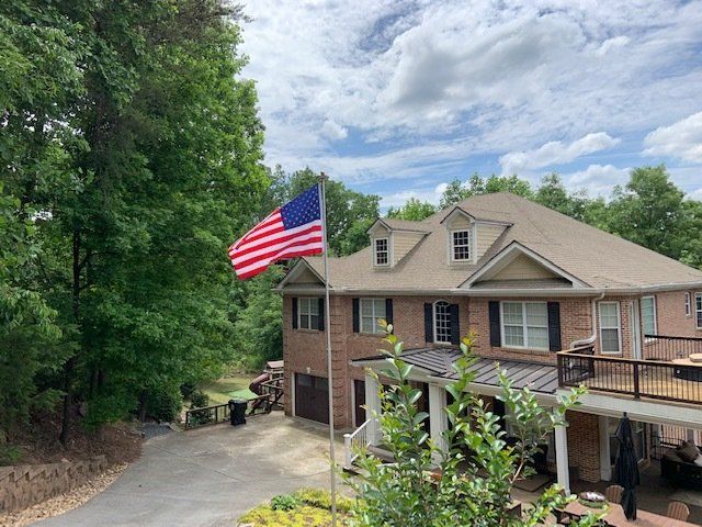 An american flag is flying in front of a large brick house.