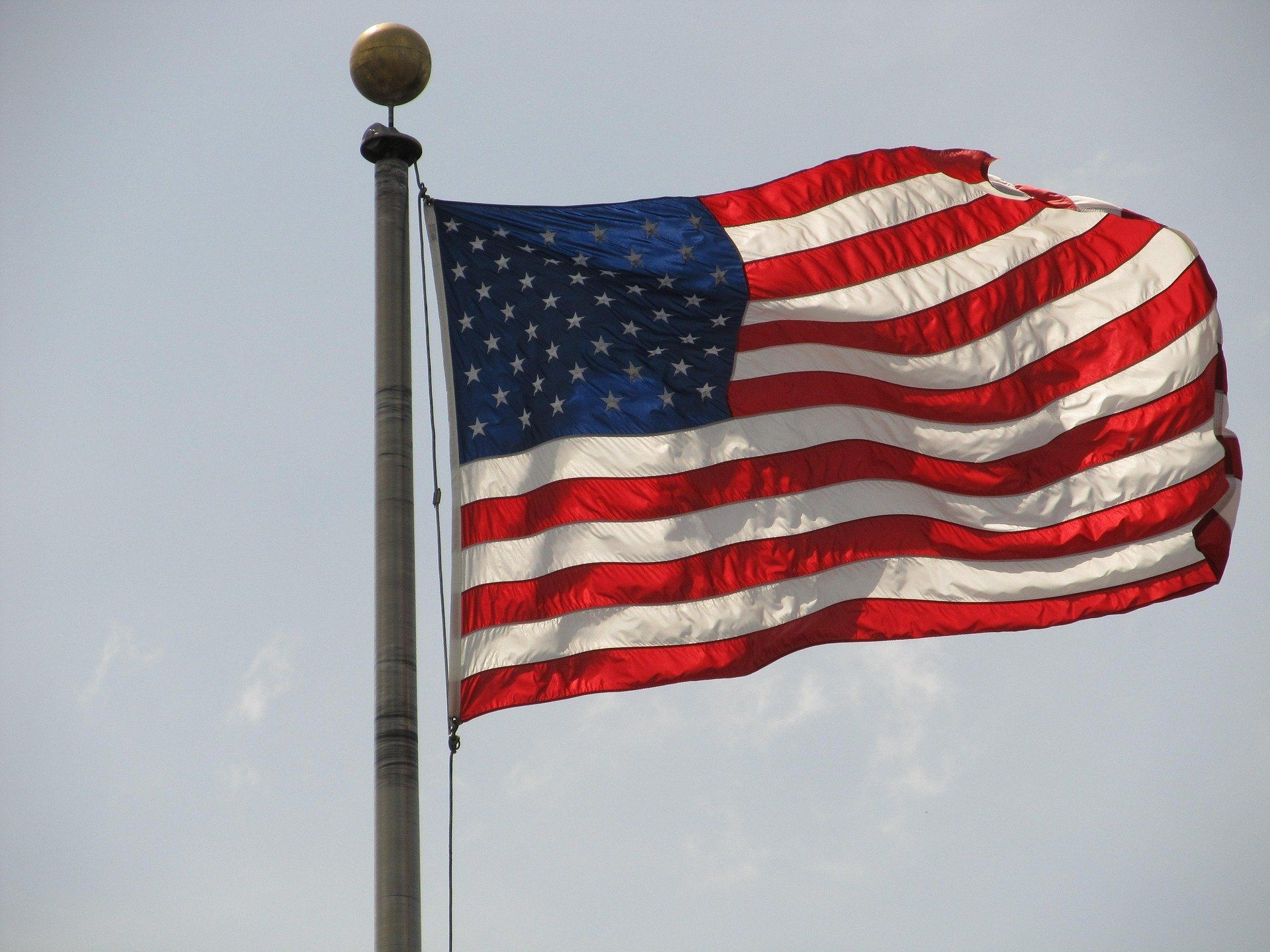 An american flag is waving in the wind on a pole