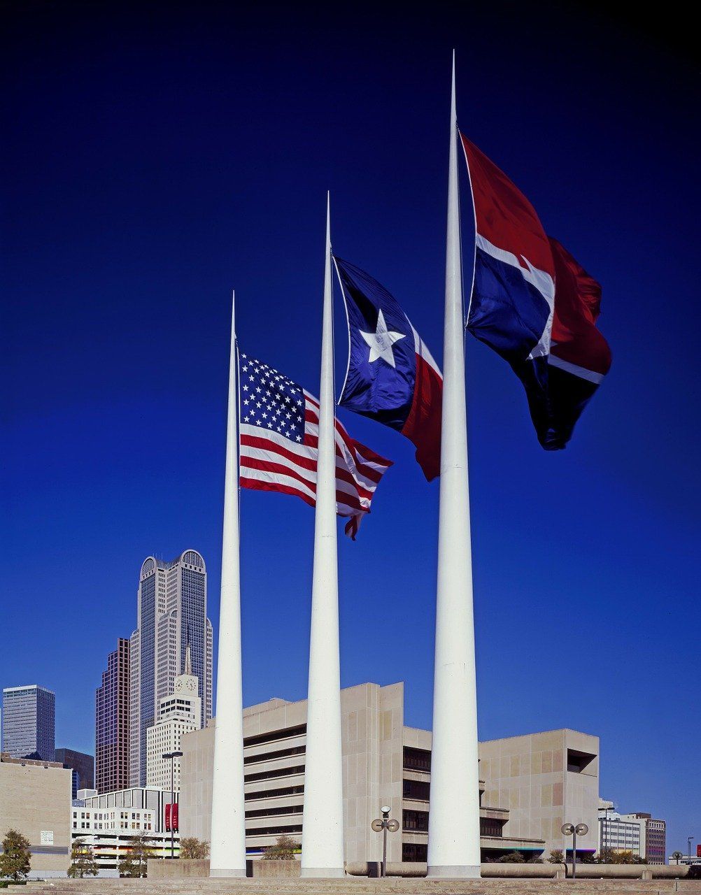 Three flags are flying in front of a building