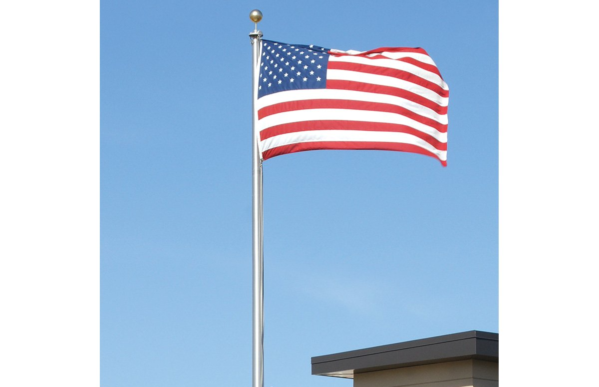 An american flag is flying in the wind in front of a building