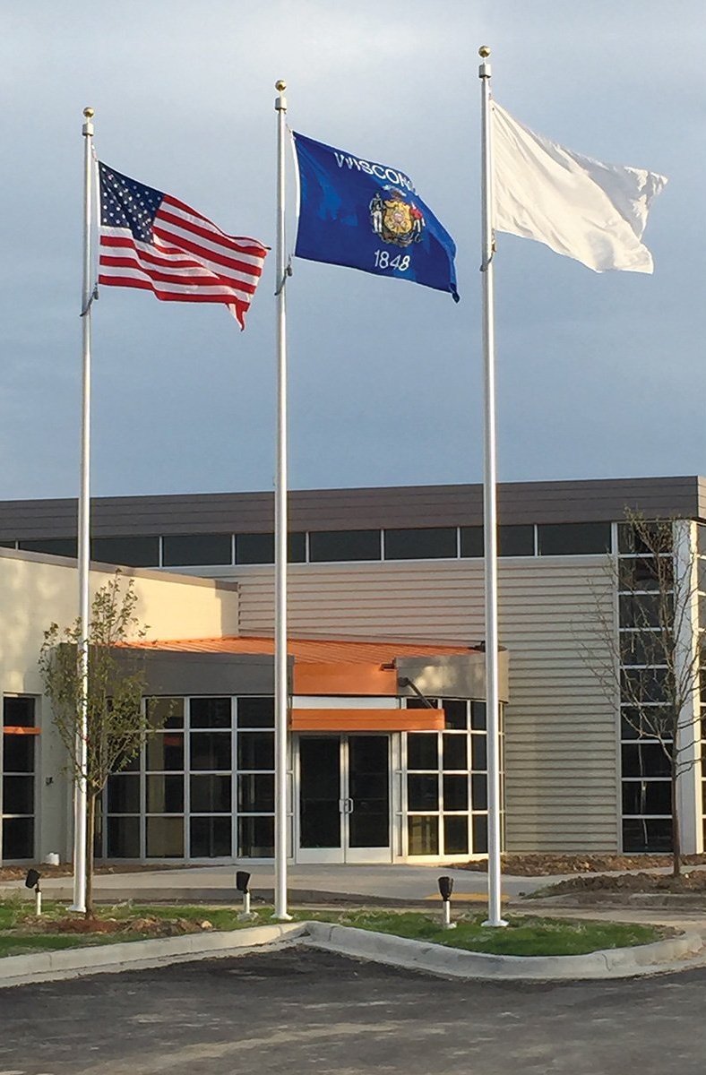 Three flags are flying in front of a building