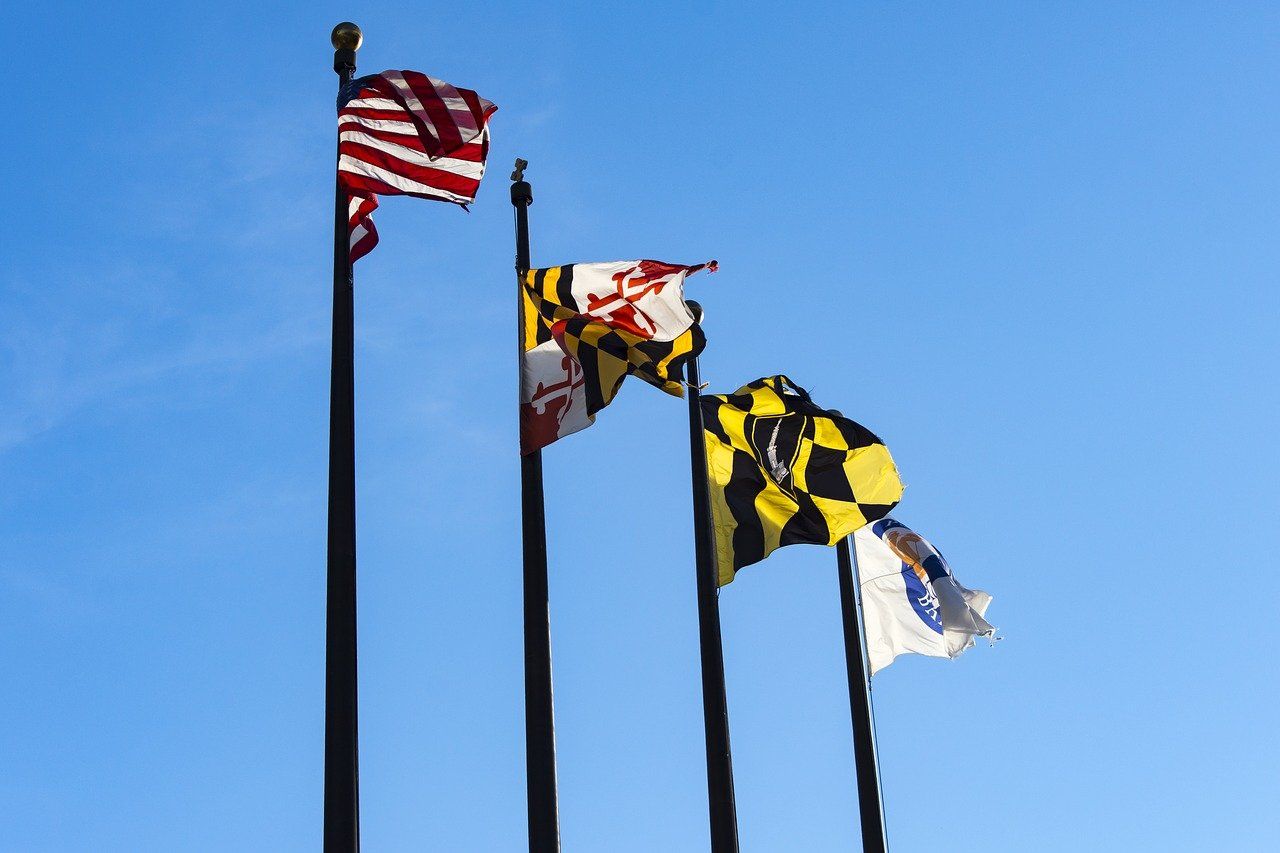Three flags are waving in the wind against a blue sky