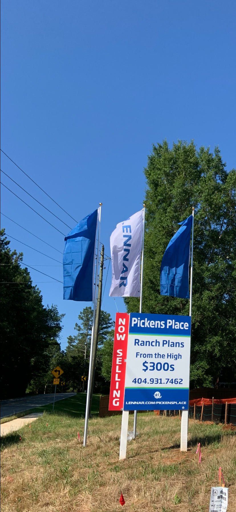 A bunch of flags are flying in the wind next to a sign.