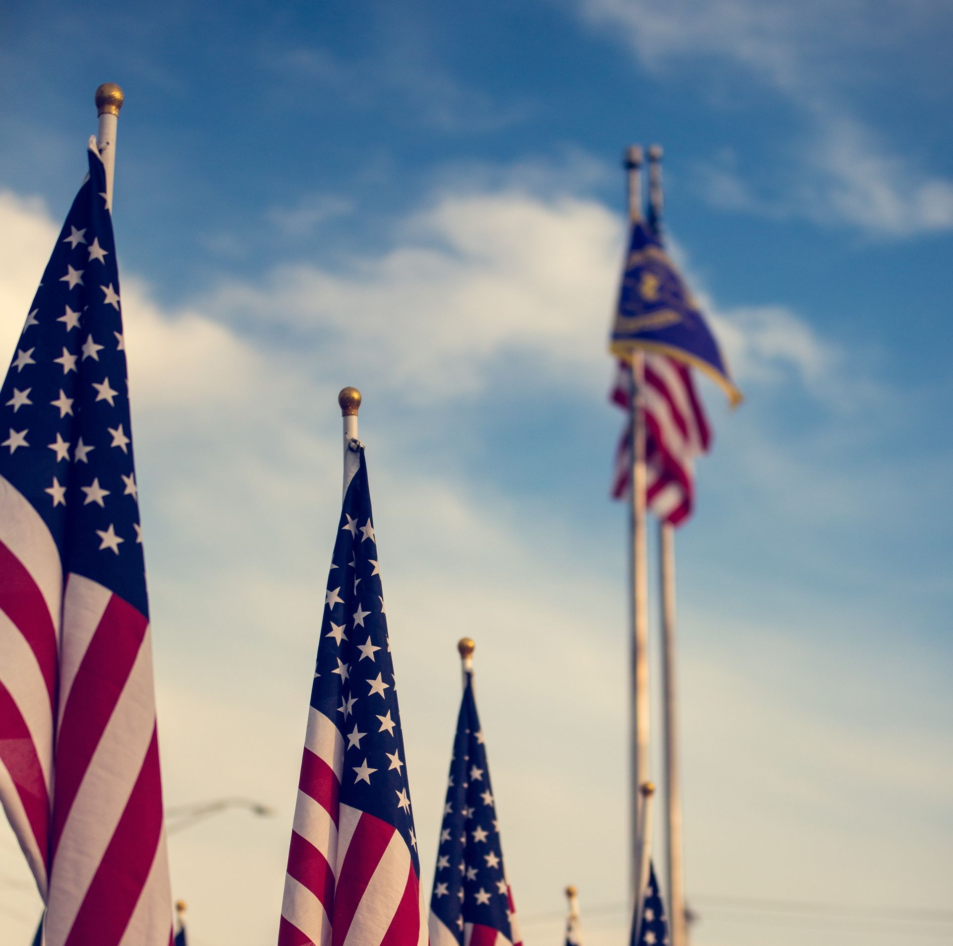 A row of american flags against a blue sky