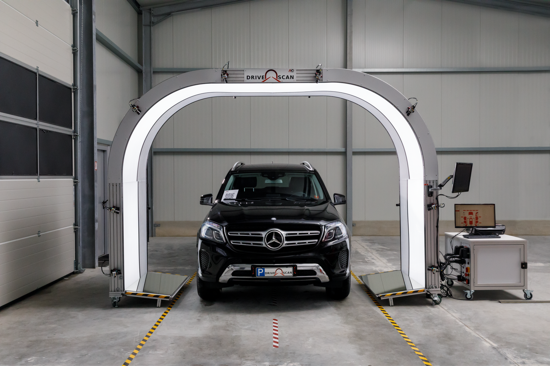 Black SUV inside a vehicle test chamber with a large white scanning arch.