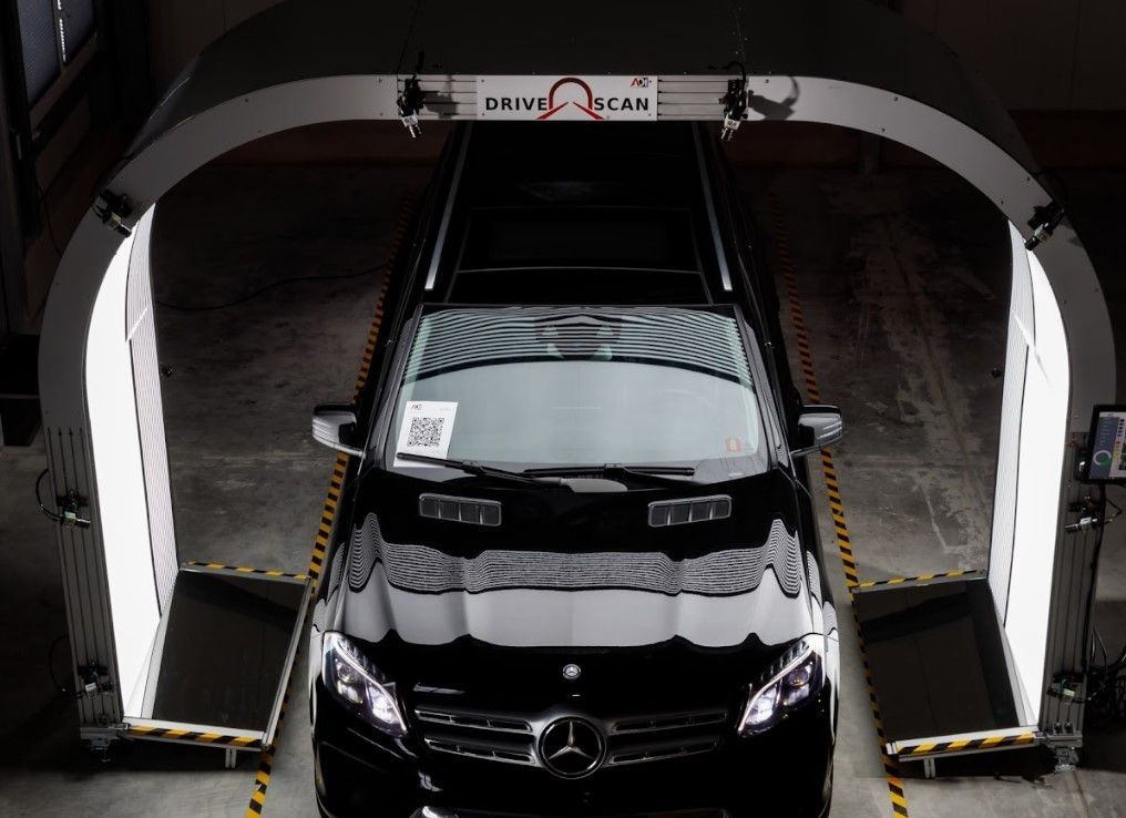 Black Mercedes van entering a drive-thru car wash with foam-covered rails on both sides