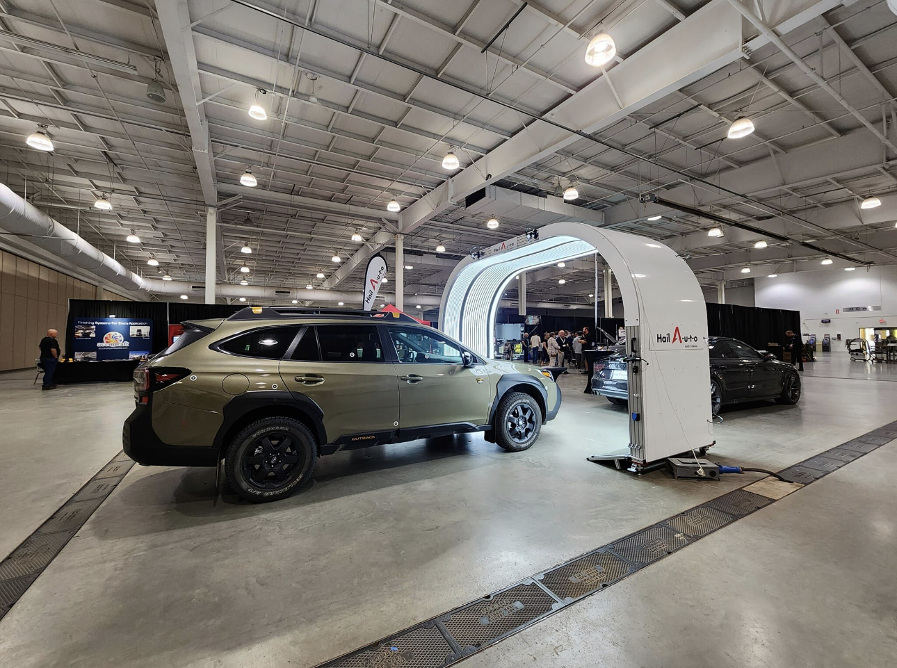 SUV in an auto showroom, passing through a white inspection arch under bright industrial lights.