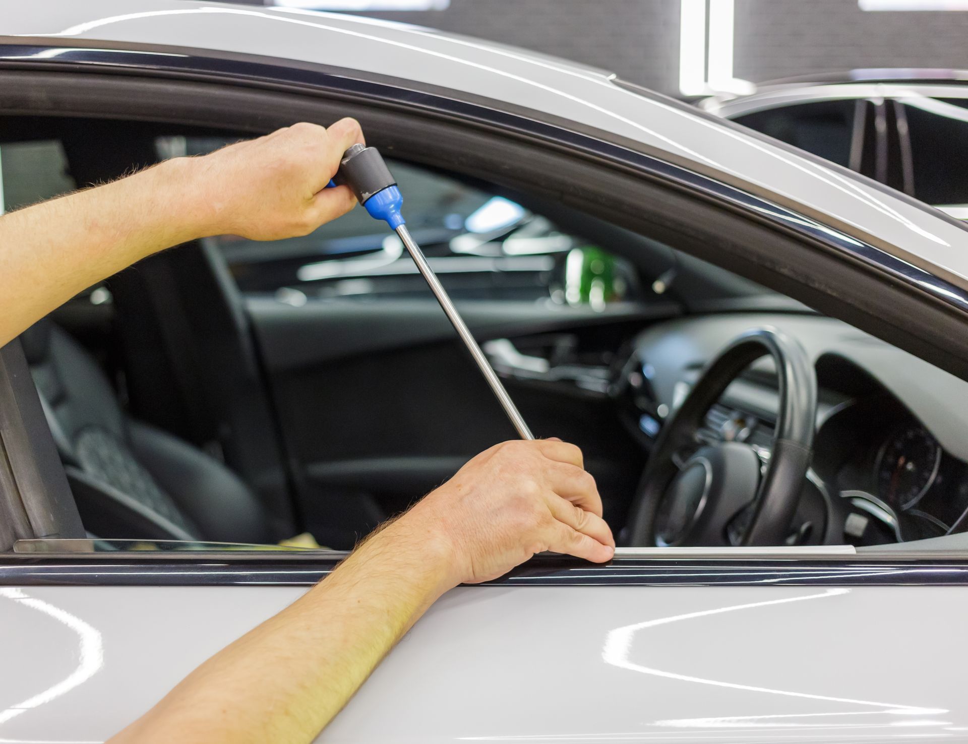 a person is working on a car with a screwdriver .