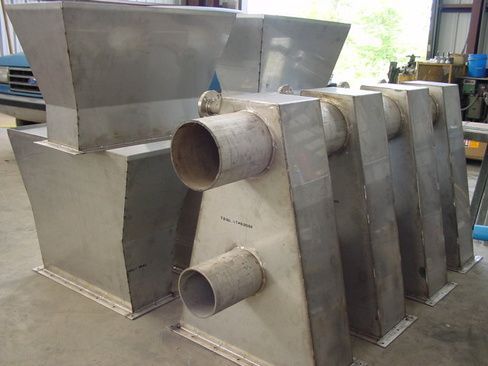 A group of stainless steel pipes sitting on top of each other on a concrete floor.