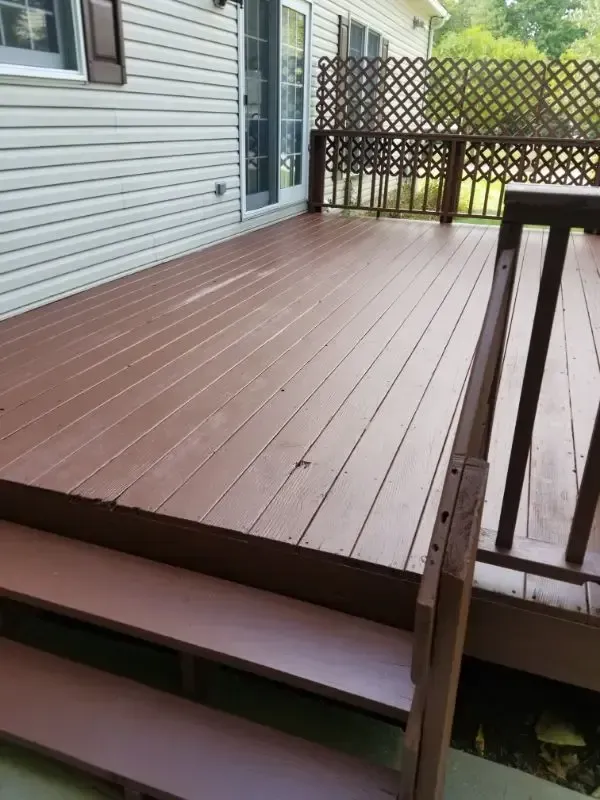 Wooden backyard deck with steps, white siding, and lattice railing beside the house