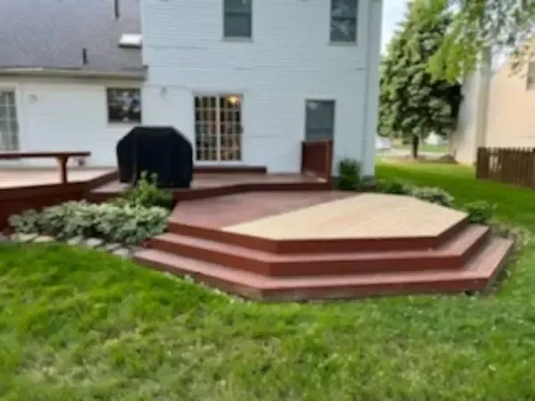 Backyard deck with wooden steps, black grill, and light gray house exterior