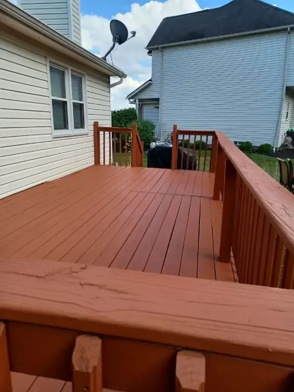 Freshly painted red wooden deck with railings between two houses in a narrow backyard