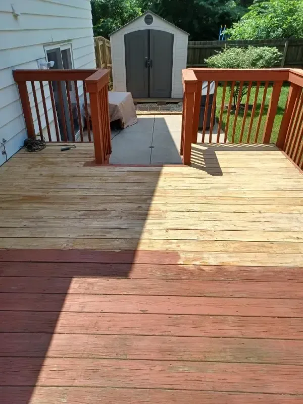 Wooden deck with stairs leading to a gray storage shed in a backyard
