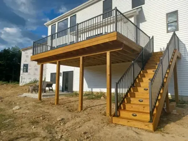Wooden deck and exterior staircase attached to a white building on a dirt lot.