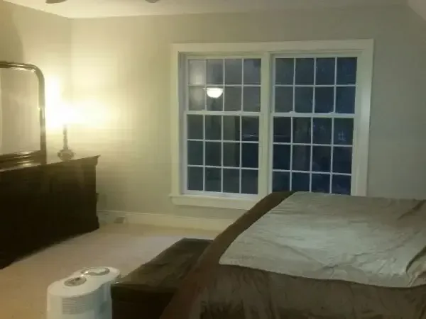 Bedroom with a bed, dresser, lamp, and window at night