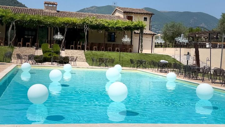Una mano posiziona un biglietto su una scaletta bianca per gli auguri di matrimonio, decorata con fiori e nastri.