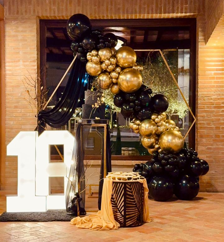 Tavolo dei dolci a tema orsacchiotto con arco di palloncini marroni e color pesca in un'ambientazione da giardino.