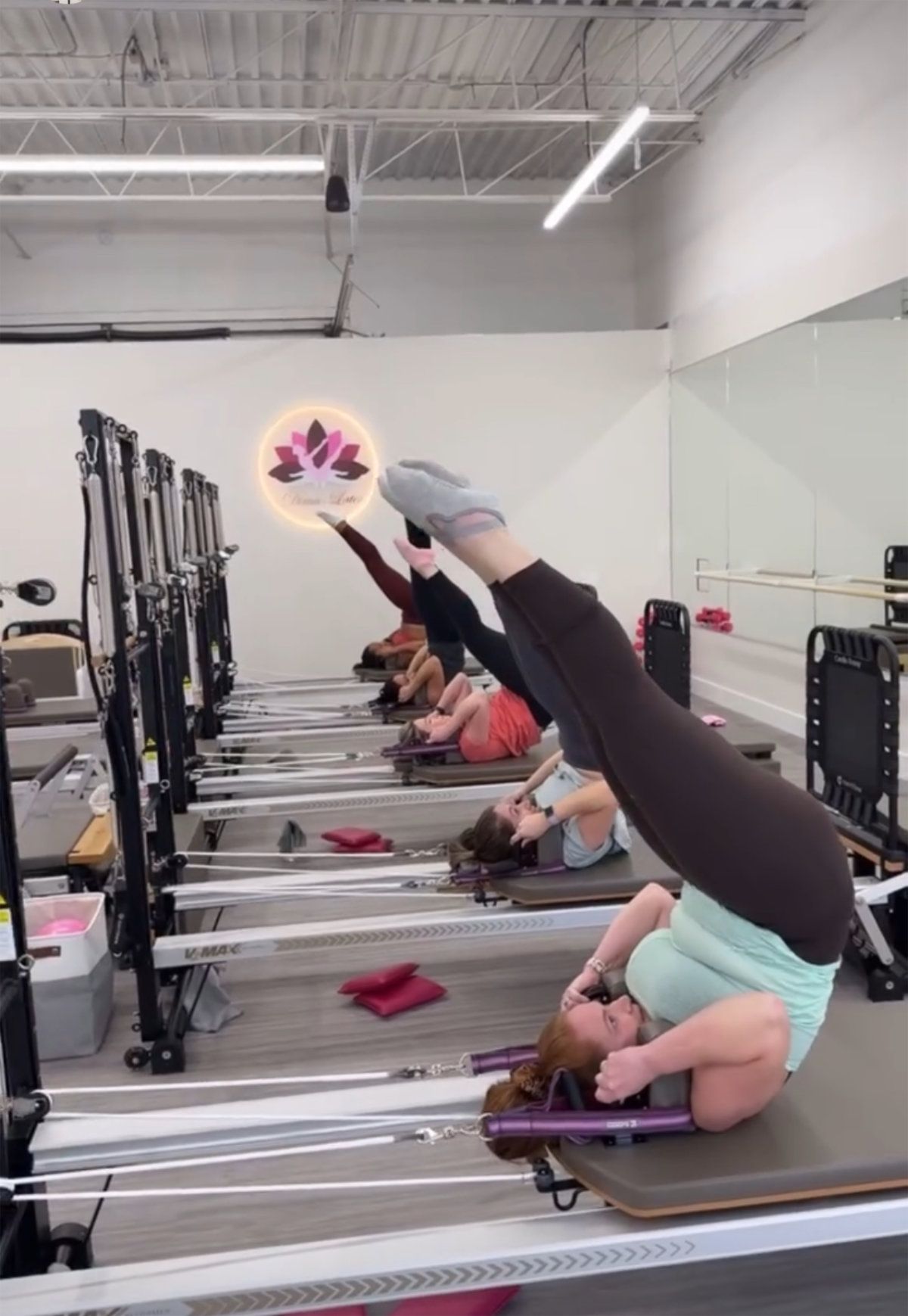 People exercising on reformer machines in a studio; lifting legs.