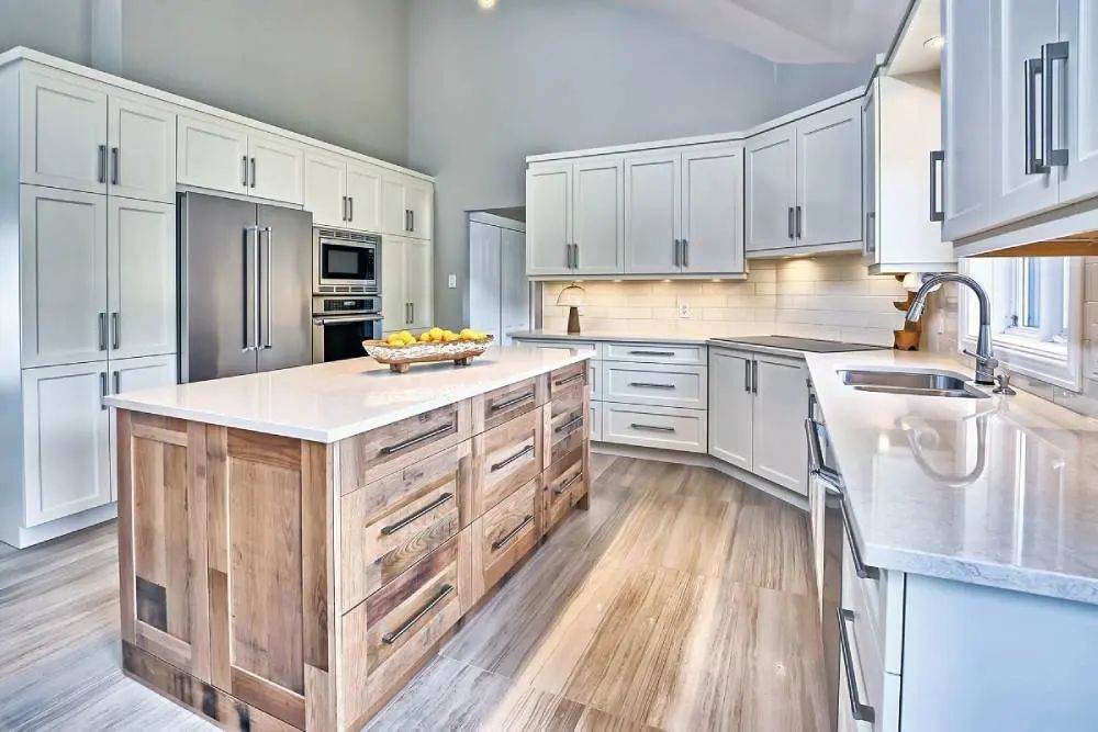 Modern kitchen with white cabinets, wood island, and stainless steel appliances.