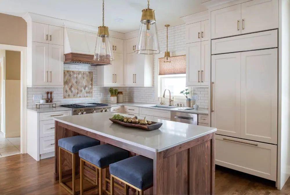 Elegant white kitchen with wood accents, island, and pendant lights.