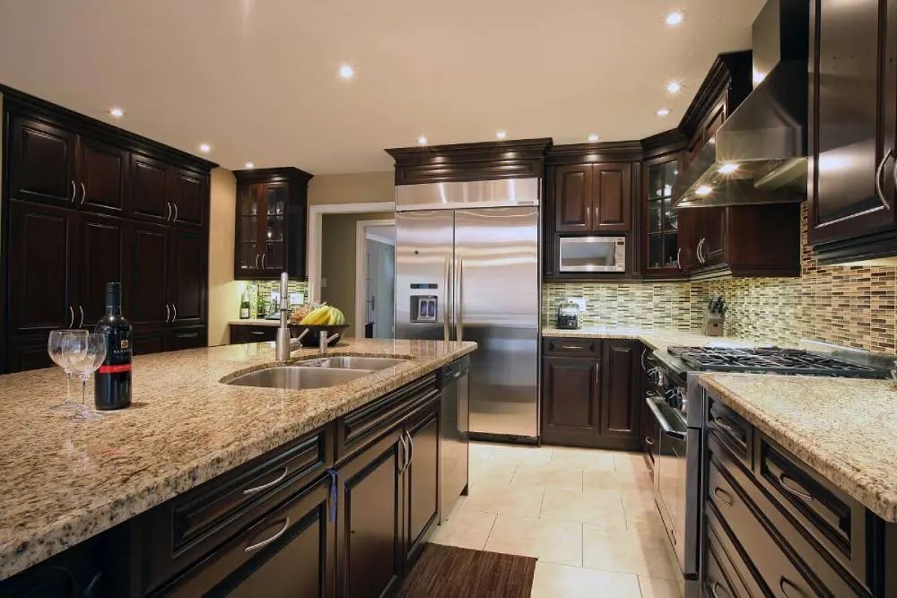 Dark wood kitchen with granite countertops, stainless steel appliances, and a central island.