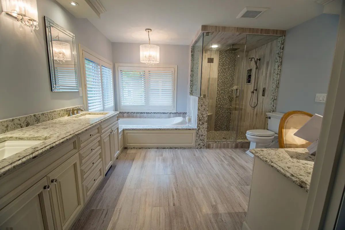 Spacious bathroom with a long vanity, glass shower, bathtub, and light wood-look flooring.