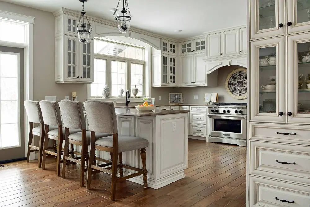 Elegant white kitchen with island, seating, and stainless steel appliances.