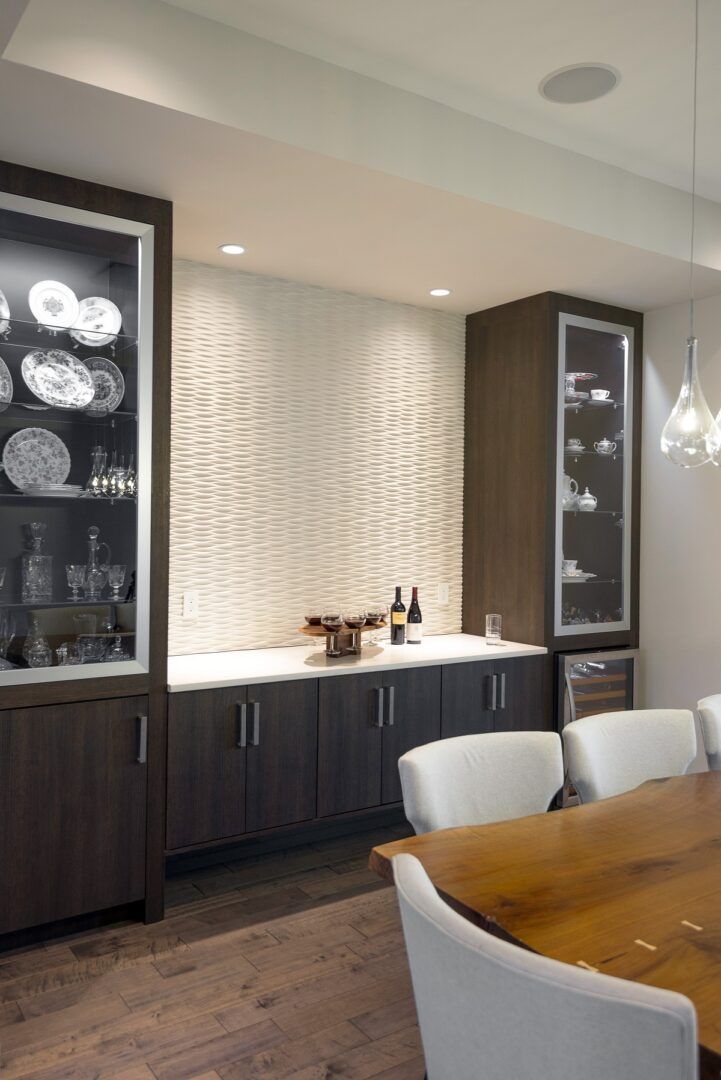 Dark wood bar area with textured wall, cabinets, and glass display cabinets.