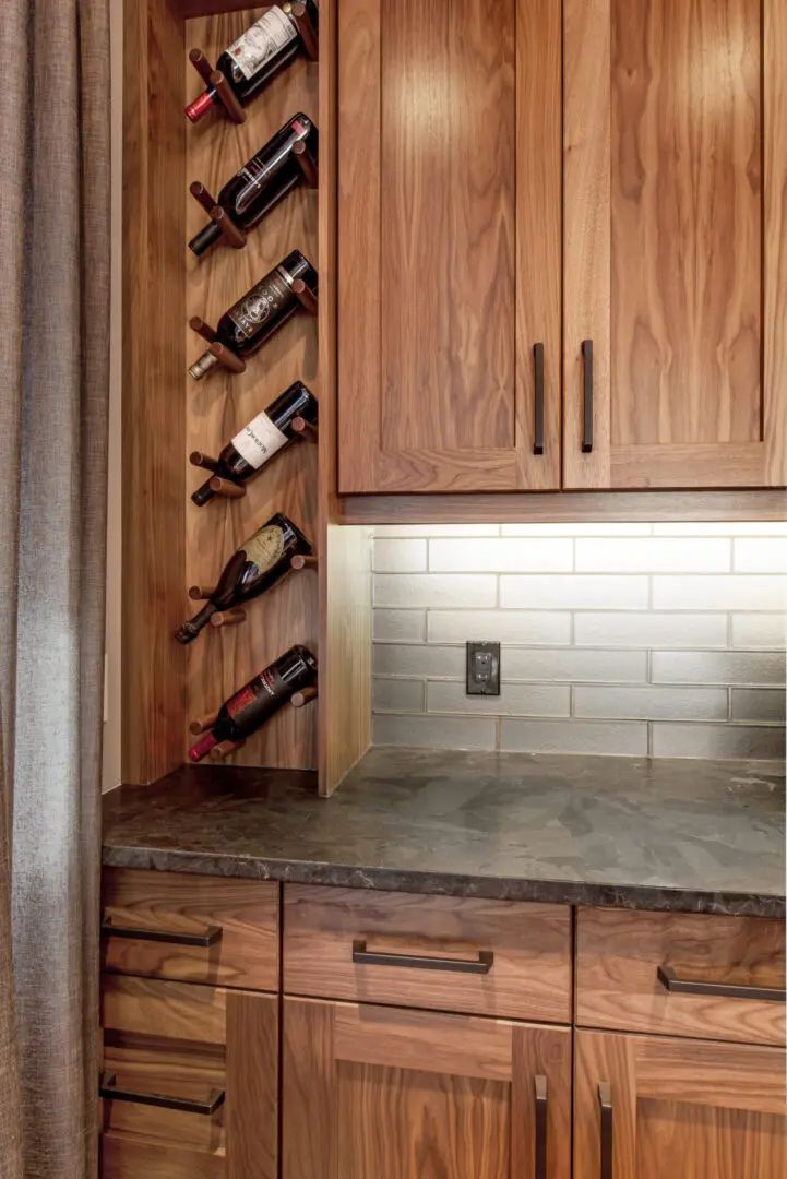 Wooden built-in kitchen cabinet with wine rack, countertop, and subway tile backsplash.