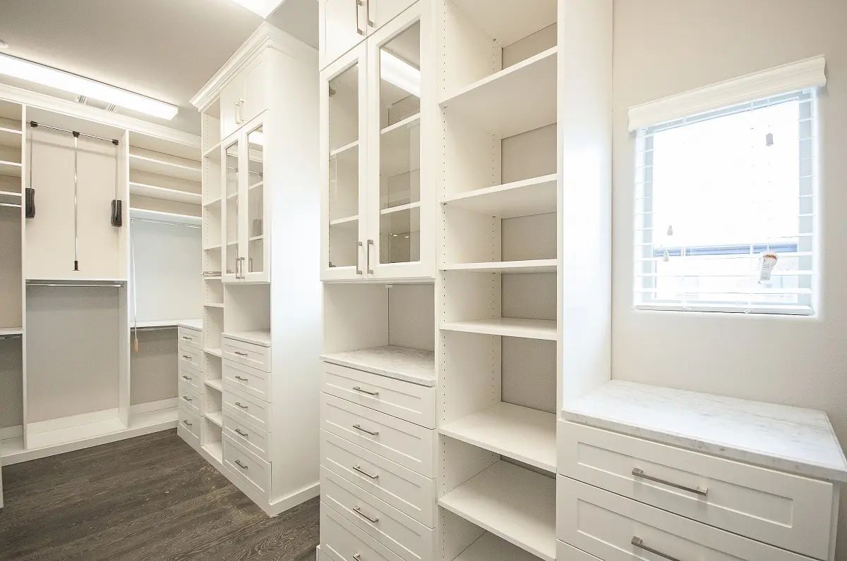 White custom closet with shelves, drawers, cabinets, and a window.