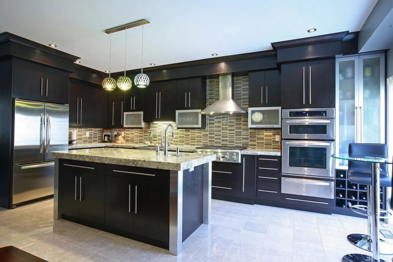 Modern kitchen with dark brown cabinets, stainless steel appliances, and a marble countertop island.