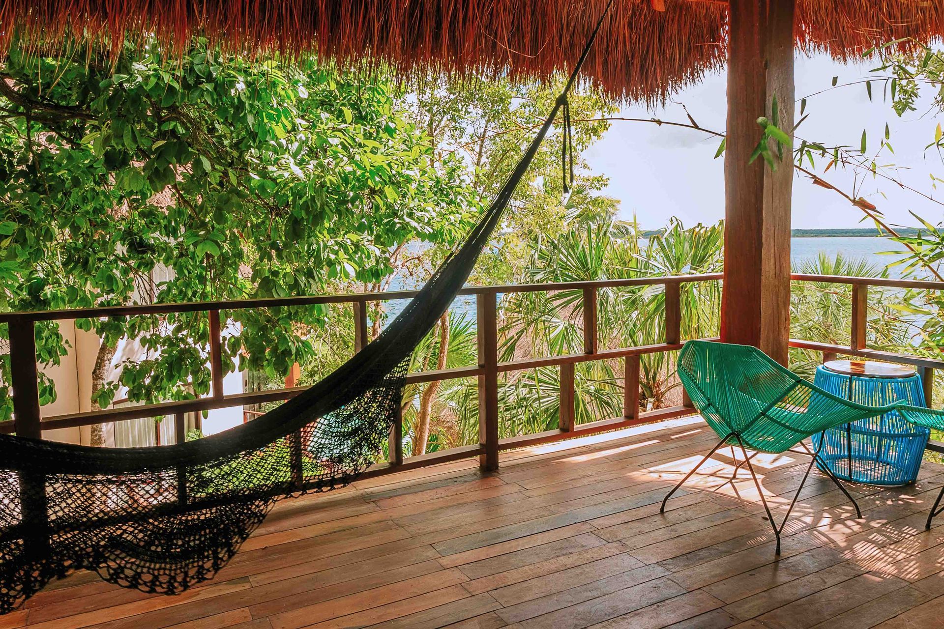 Terraza frente a la playa con hamaca y sillas coloridas con vistas a la laguna de Bacalar